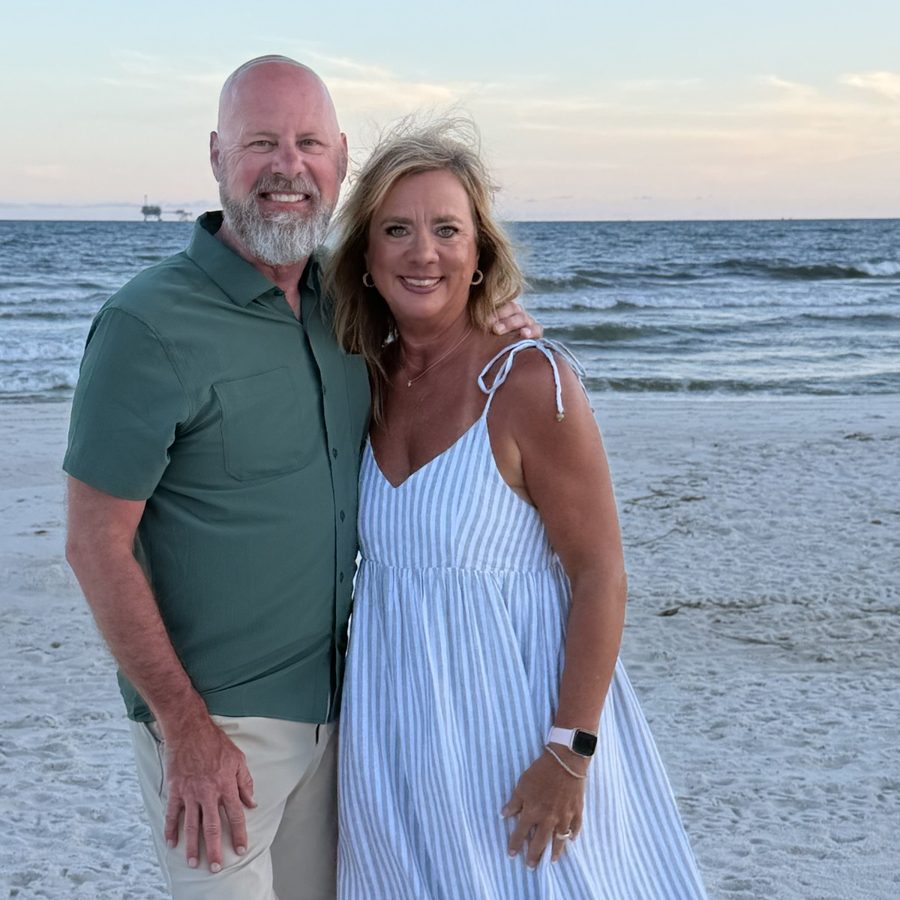 Joe and Danielle Cook standing together on a beach at sunset